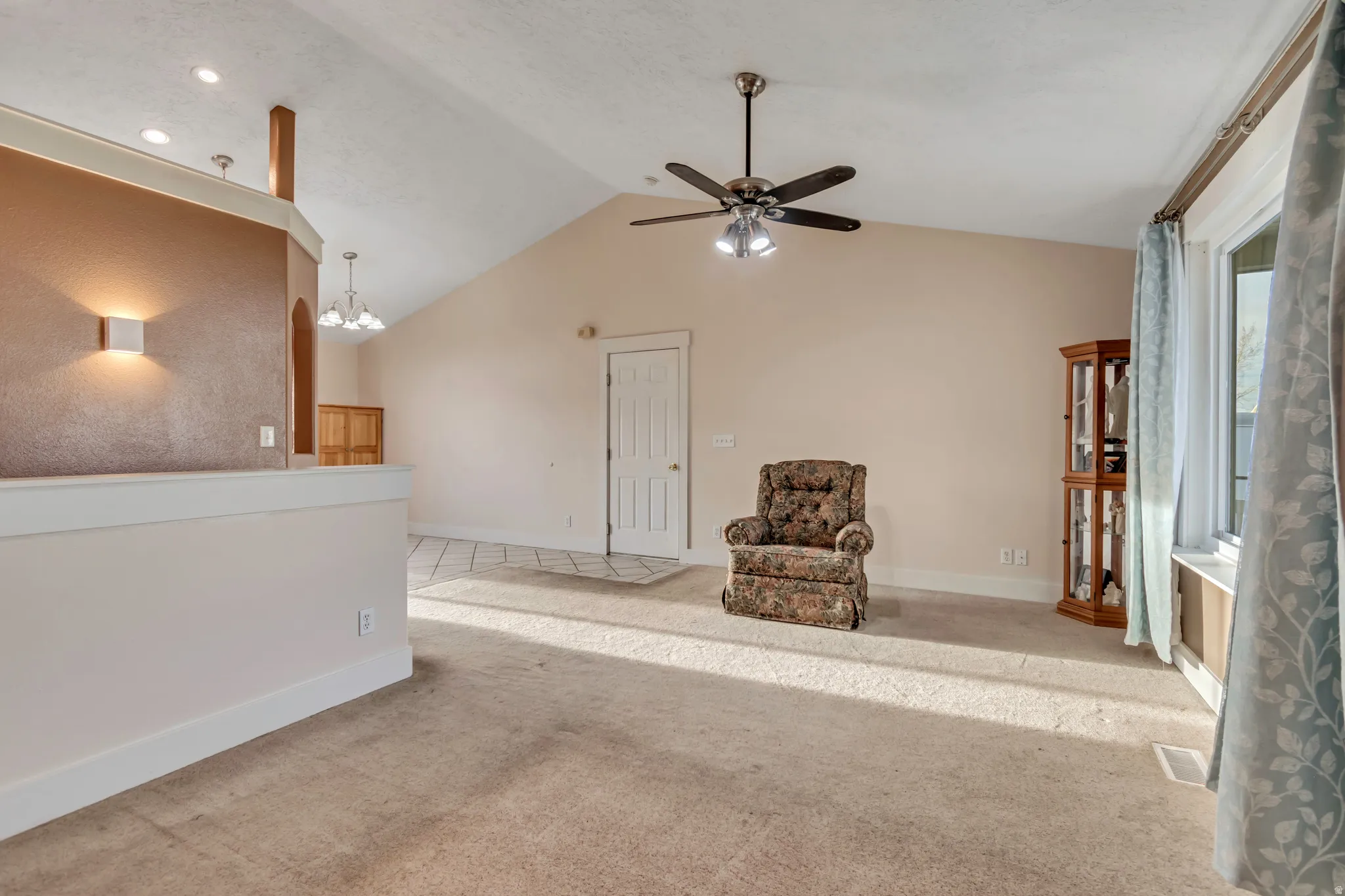 Sitting room featuring ceiling fan, carpet flooring, hanging lights, and a high ceiling