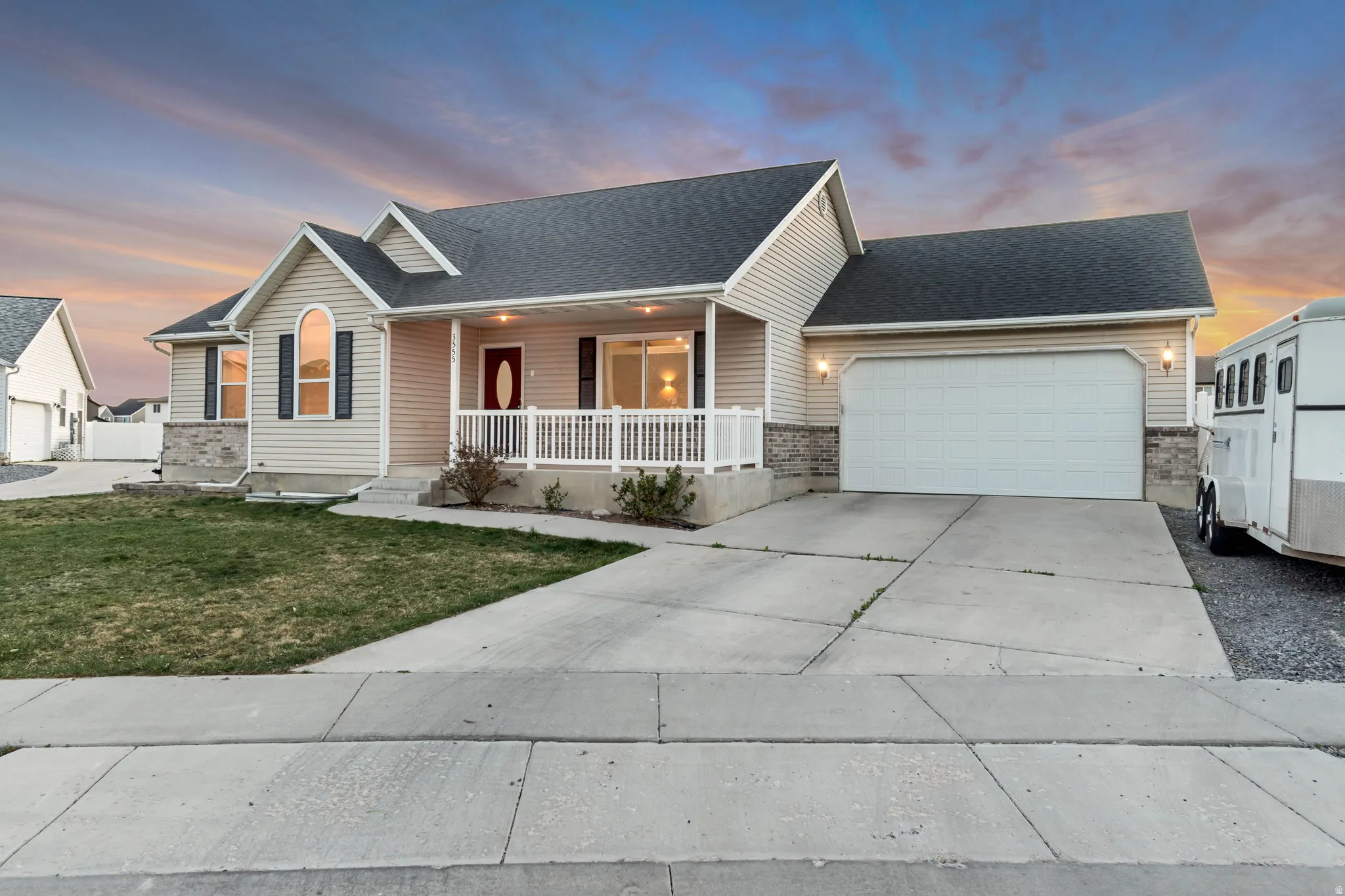 View of front of house with a porch, a garage, driveway, a front yard, and a shingled roof