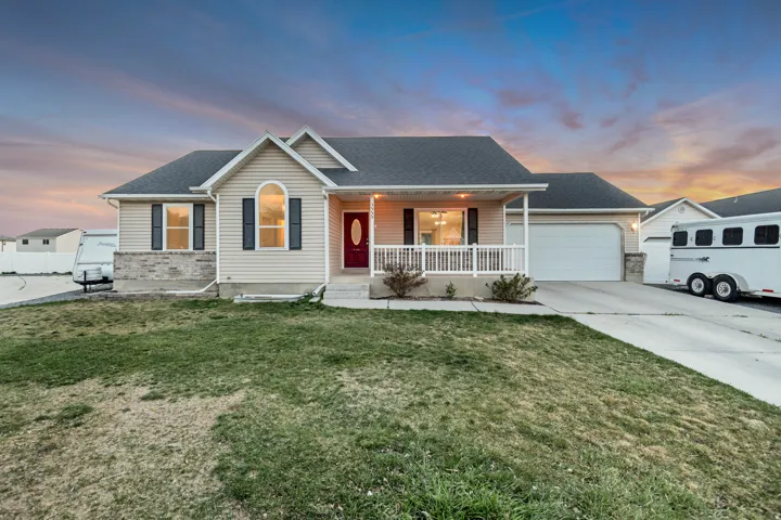 Ranch-style home featuring covered porch, driveway, a front yard, and an attached garage