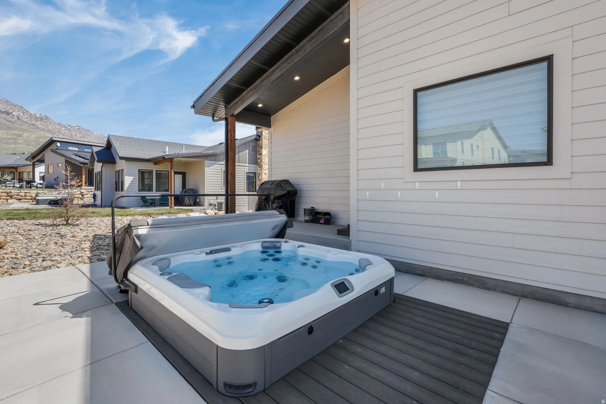 Outdoor hot tub with integrated lighting, set on composite decking and concrete patio