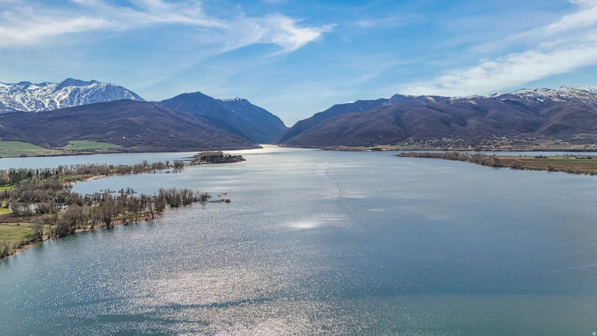 Expansive waterfront setting with surrounding mountains and a clear blue sky overhead
