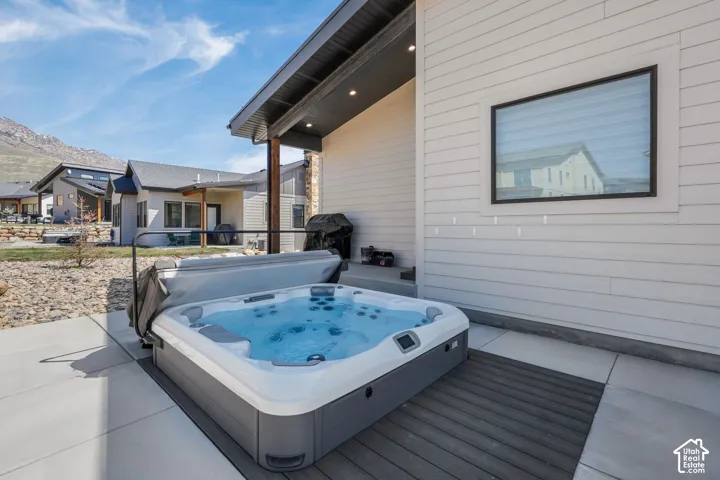 Outdoor hot tub with integrated lighting, set on composite decking and concrete patio