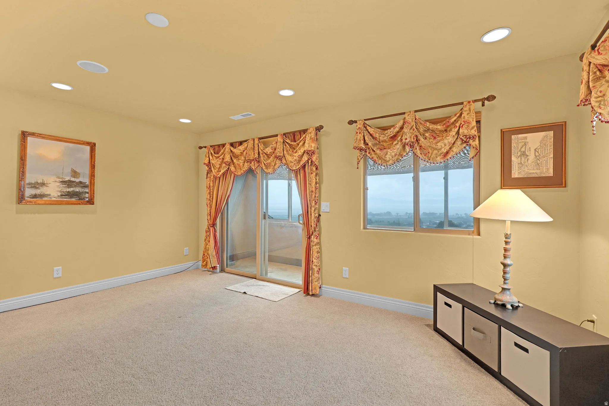 Carpeted room featuring recessed lighting, a sliding glass door to an outdoor patio, and an additional window