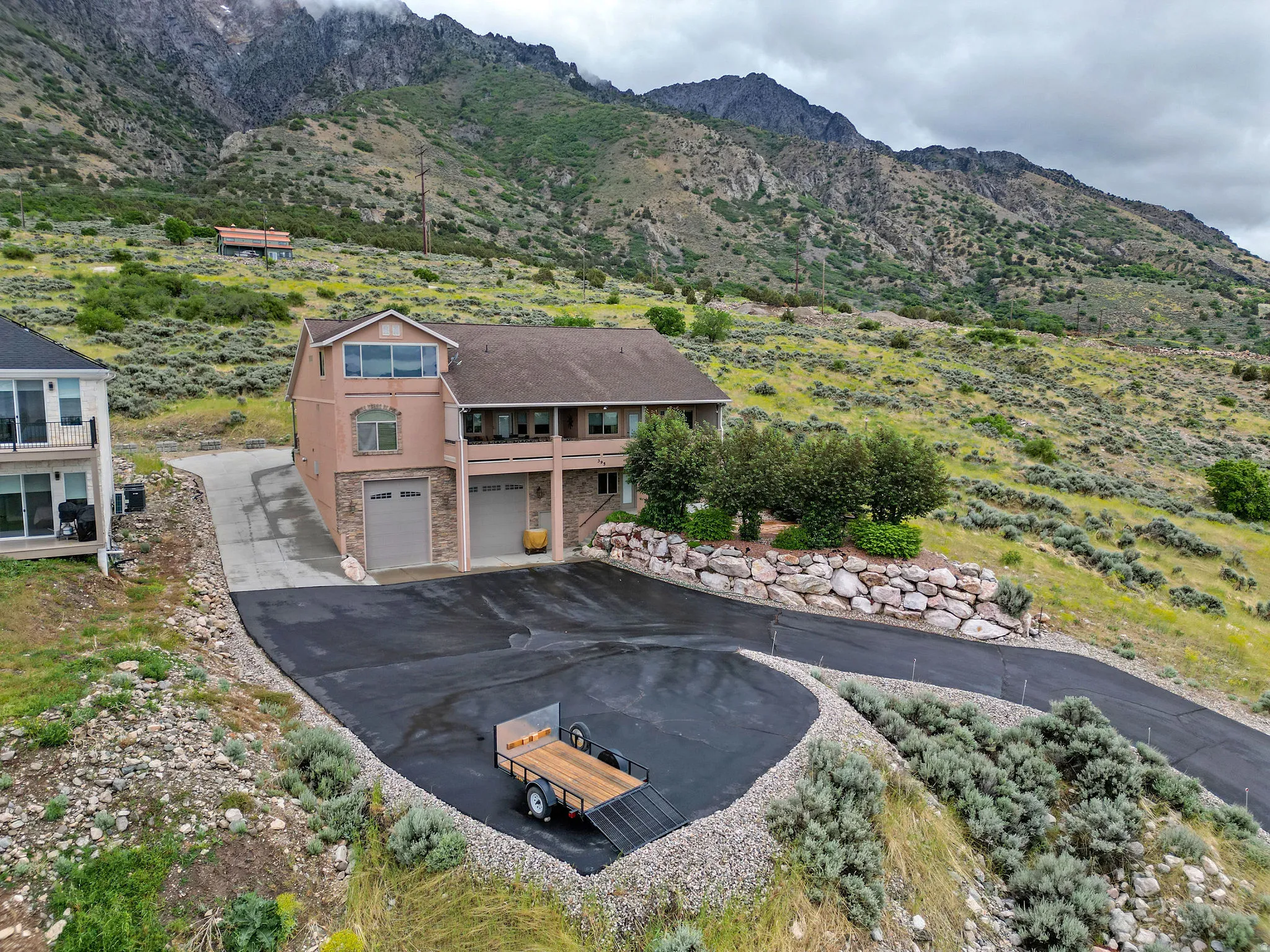 Multi-level residence featuring a stucco and stone exterior, multiple balconies, a two-car garage, an additional single-car garage, and a newly paved driveway