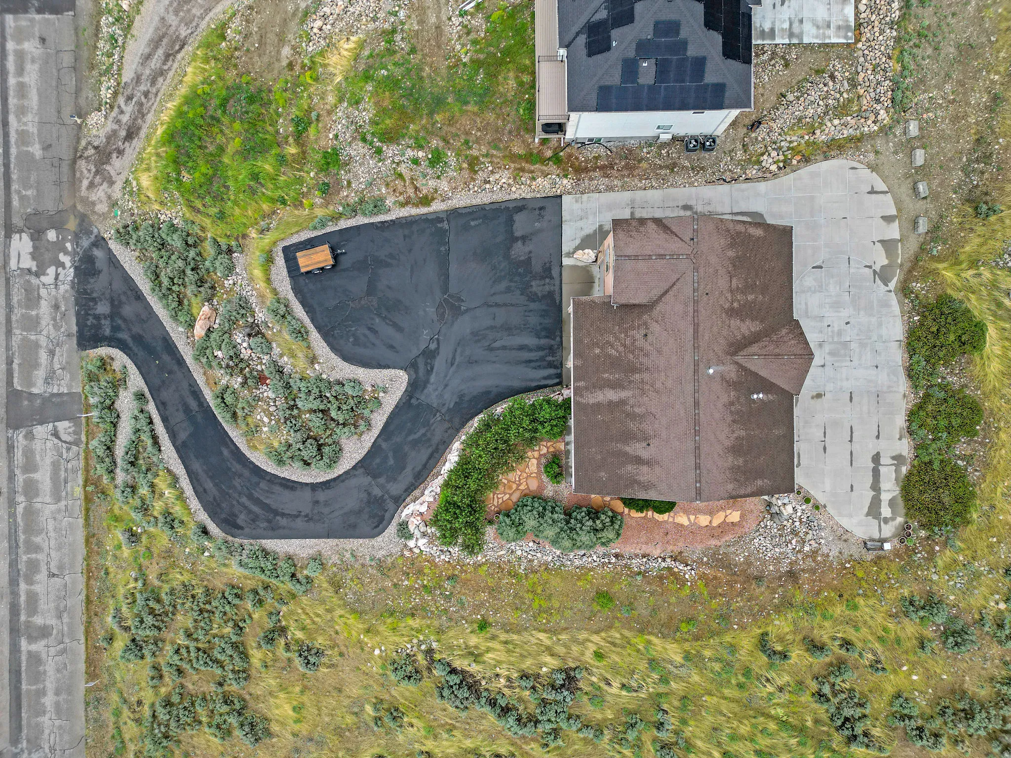 Residential property featuring a brown shingle roof, a paved driveway, and a concrete patio