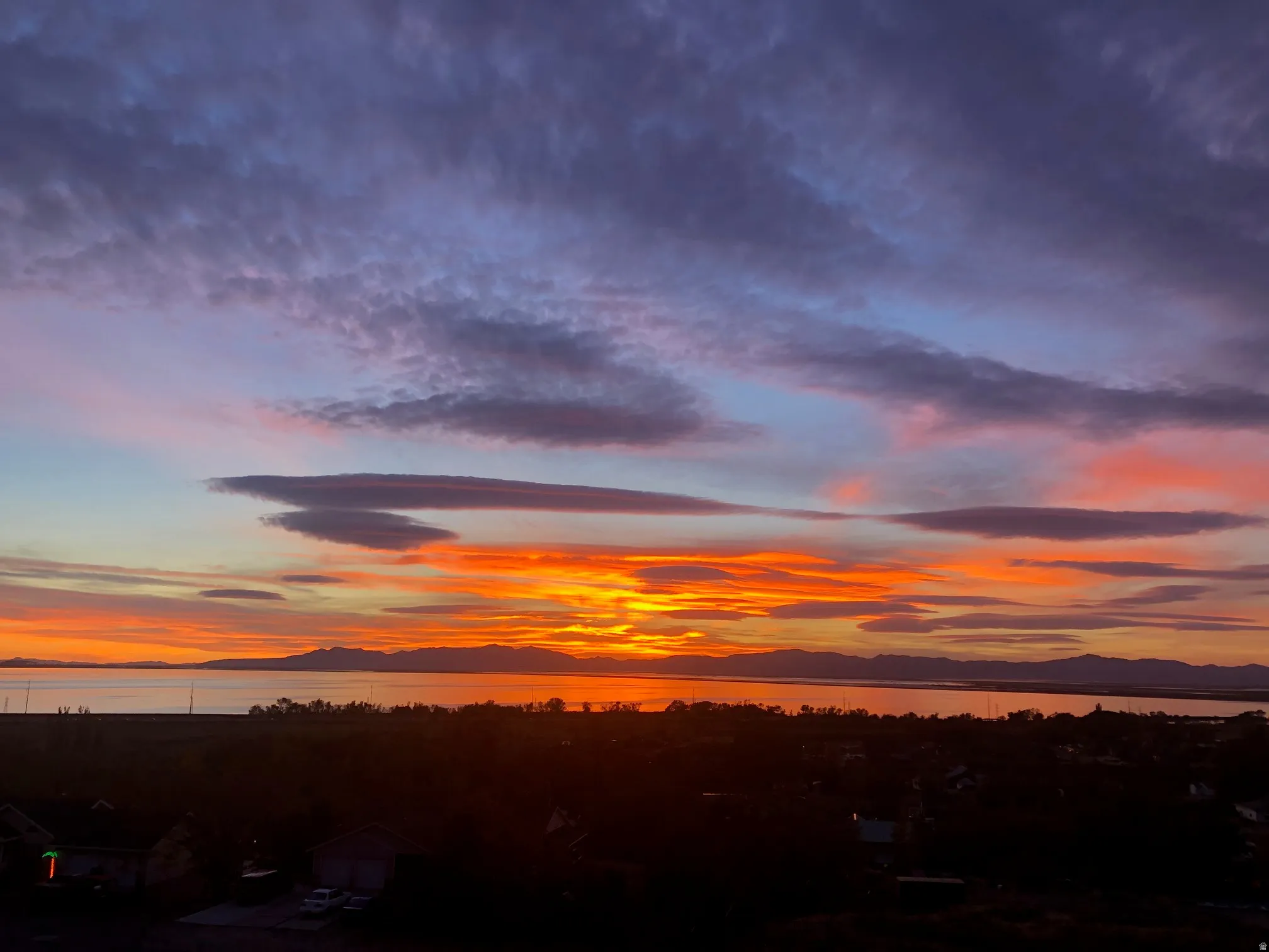 Expansive water frontage with mountain backdrop and vibrant sunset