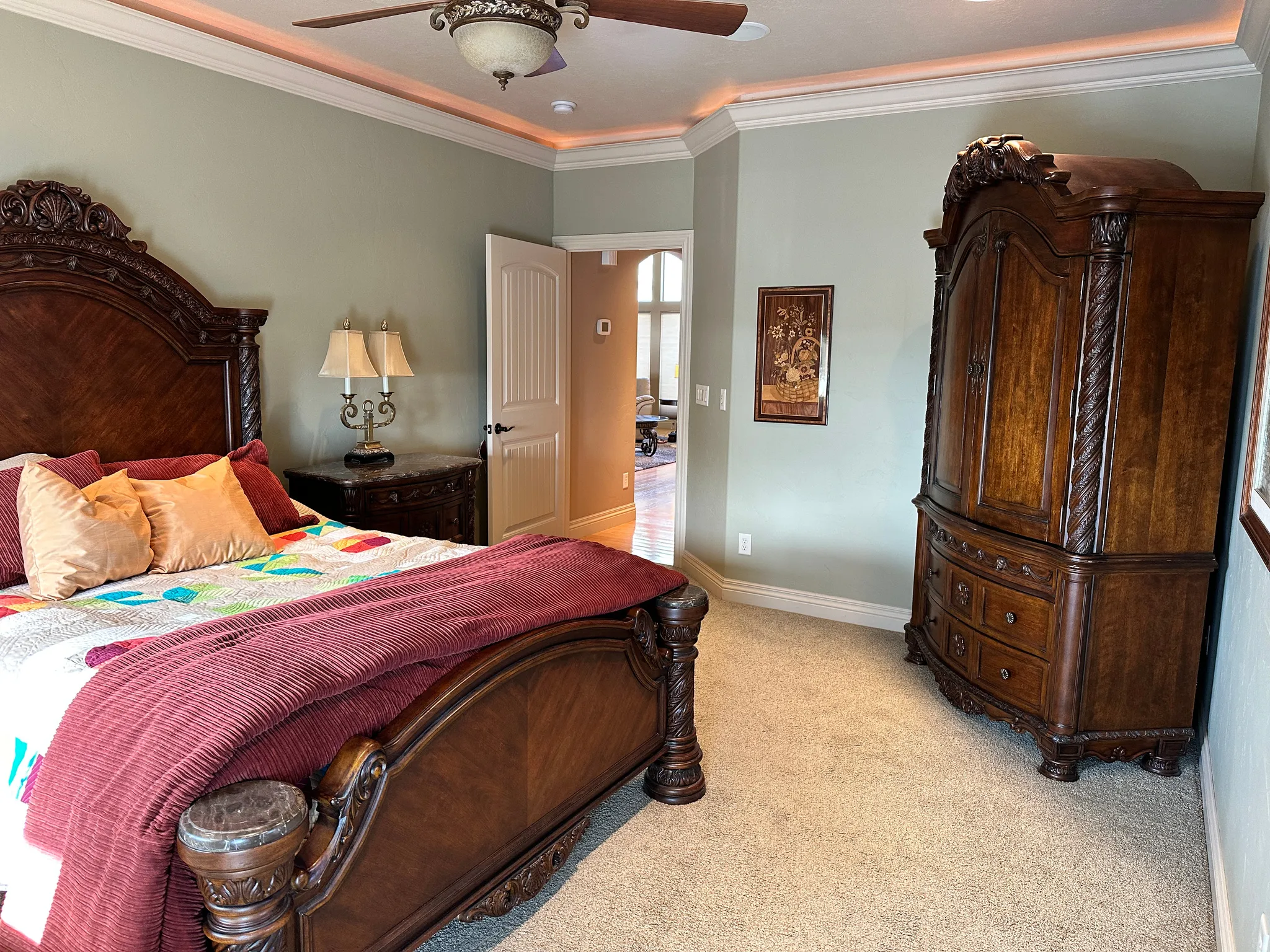 Primary bedroom with crown molding and tray ceiling with lighting