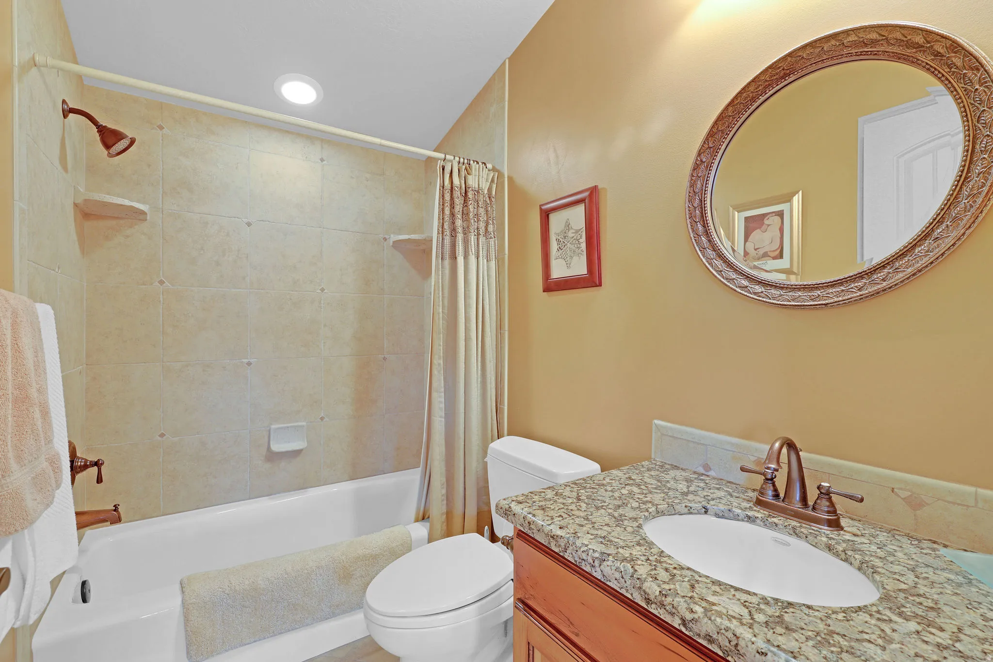 Bathroom featuring a vanity with granite countertop, undermount sink, and bronze-finish faucet