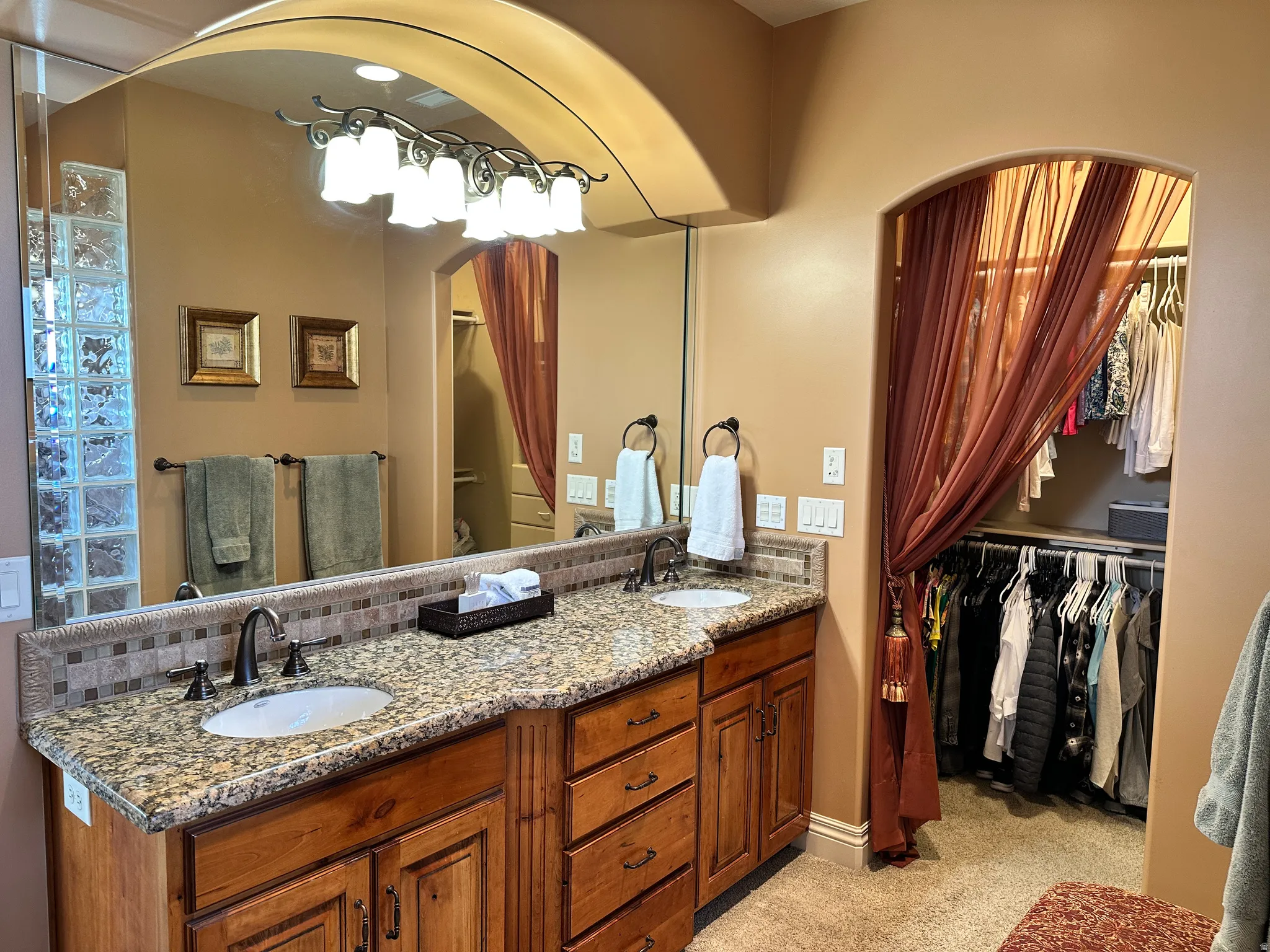 Bathroom with double vanity, a spacious closet, and decorative backsplash