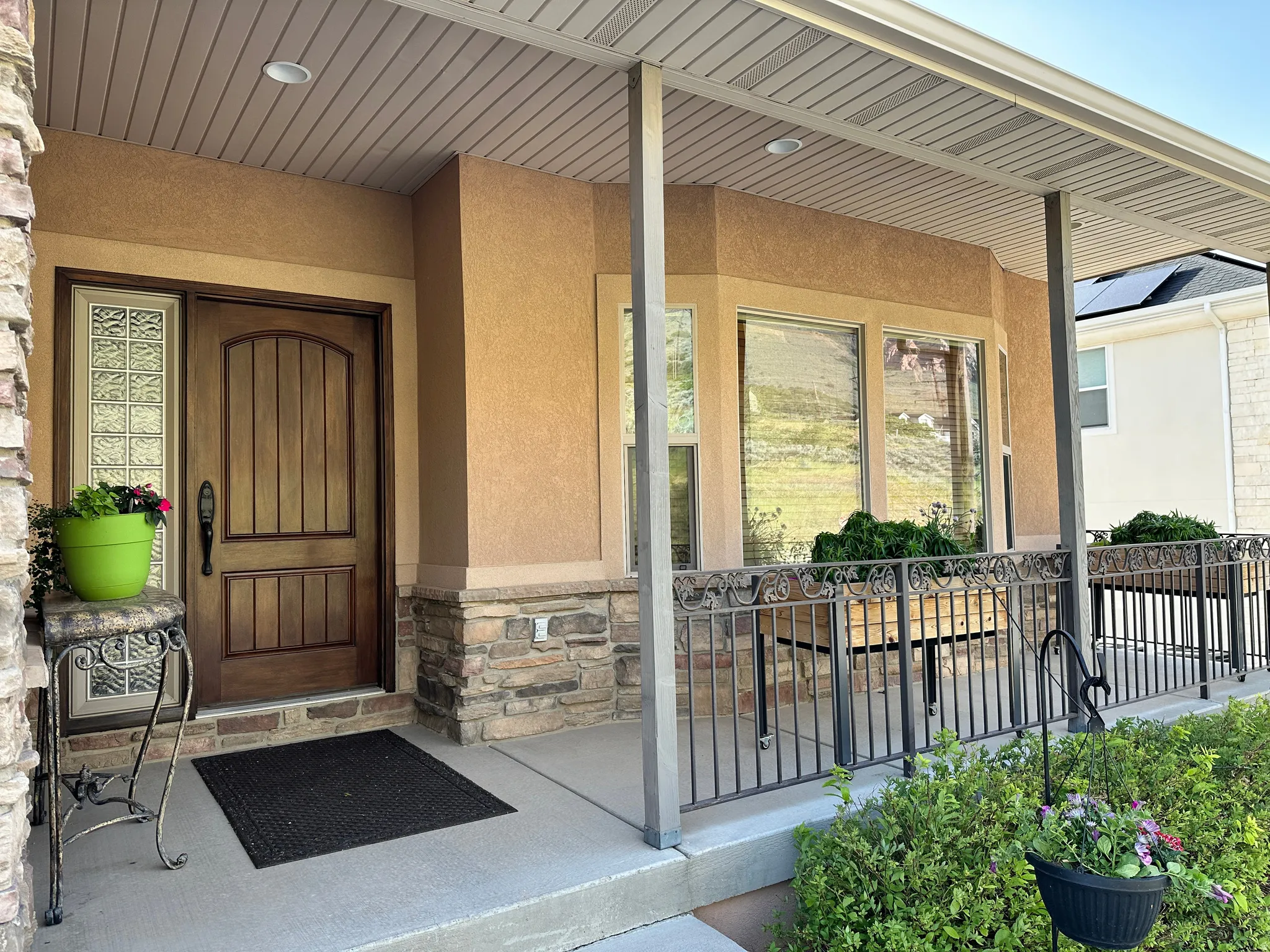 Entrance to property with a porch, stucco siding, and stone siding
