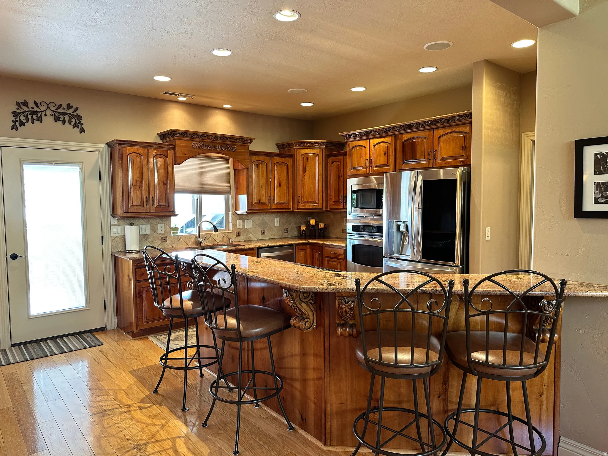 Kitchen with wood cabinetry, stainless steel appliances, granite countertops, and backsplash