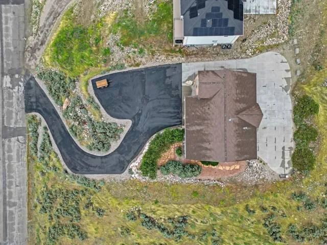 Residential property featuring a brown shingle roof, a paved driveway, and a concrete patio