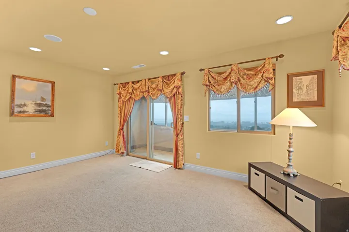 Carpeted room featuring recessed lighting, a sliding glass door to an outdoor patio, and an additional window