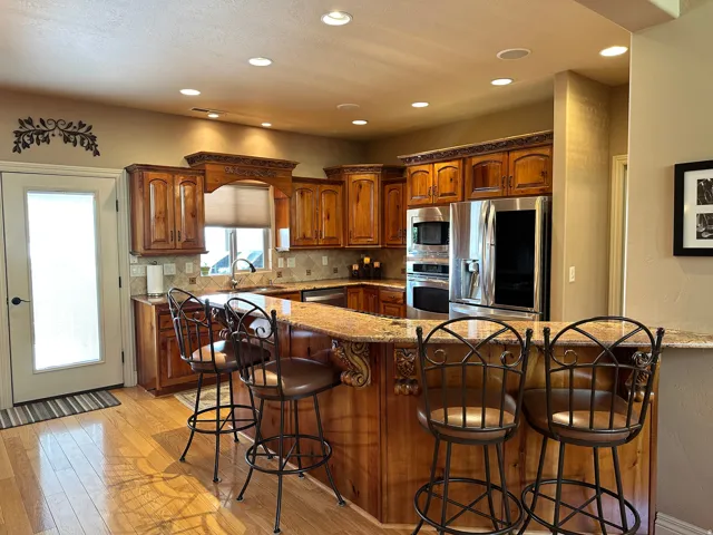 Kitchen with wood cabinetry, stainless steel appliances, granite countertops, and backsplash
