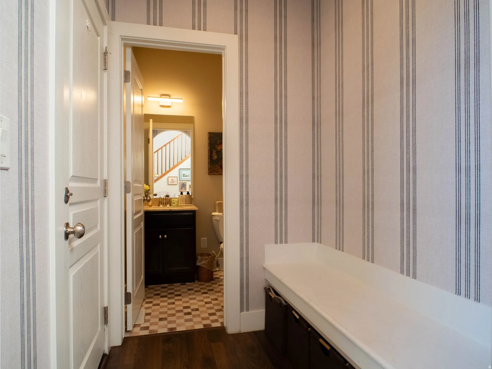 Bathroom with vanity, wallpapered walls, and dark wood finished floors