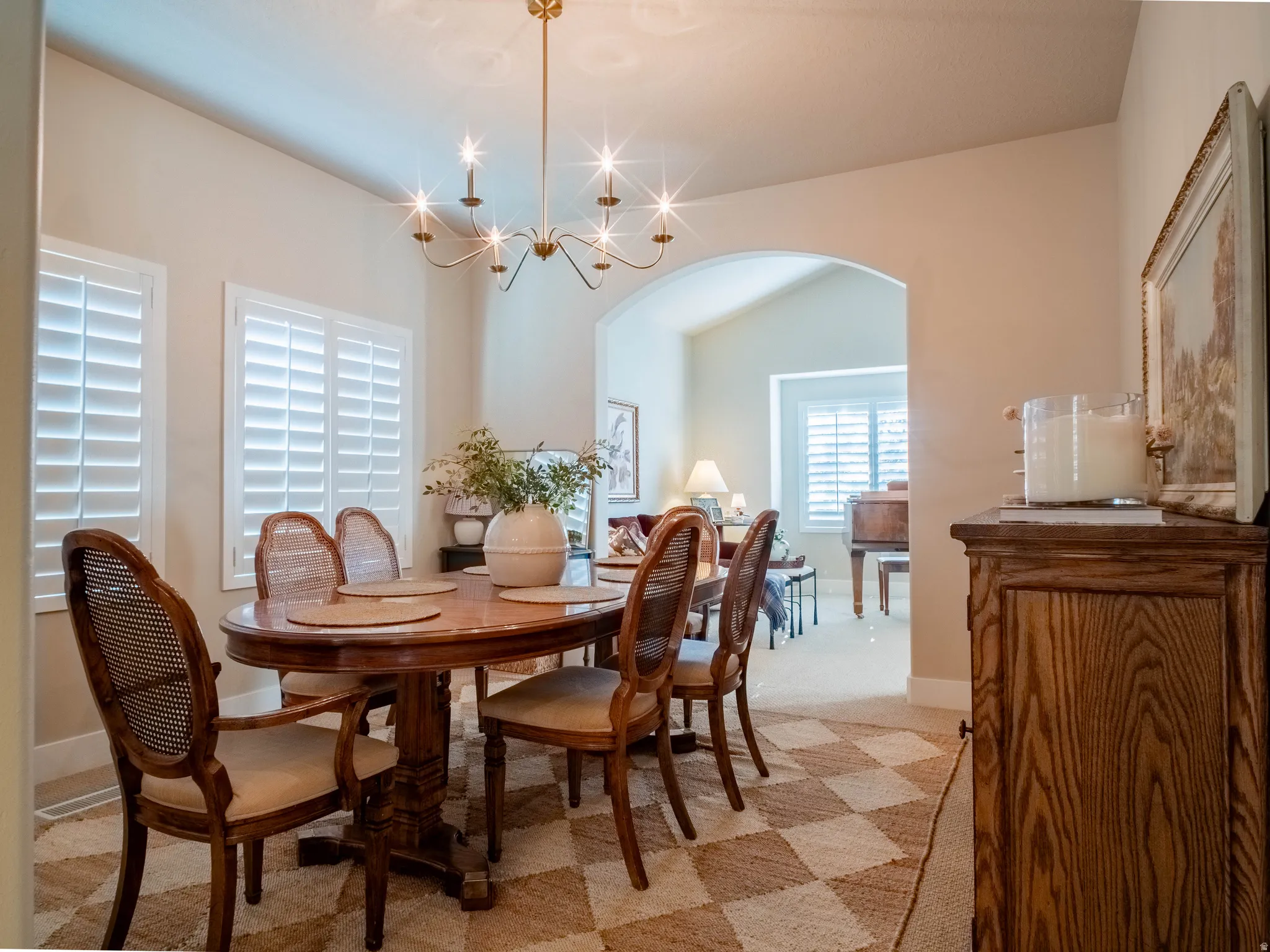 Dining room with arched walkways, light carpet, hanging lights, and vaulted ceiling