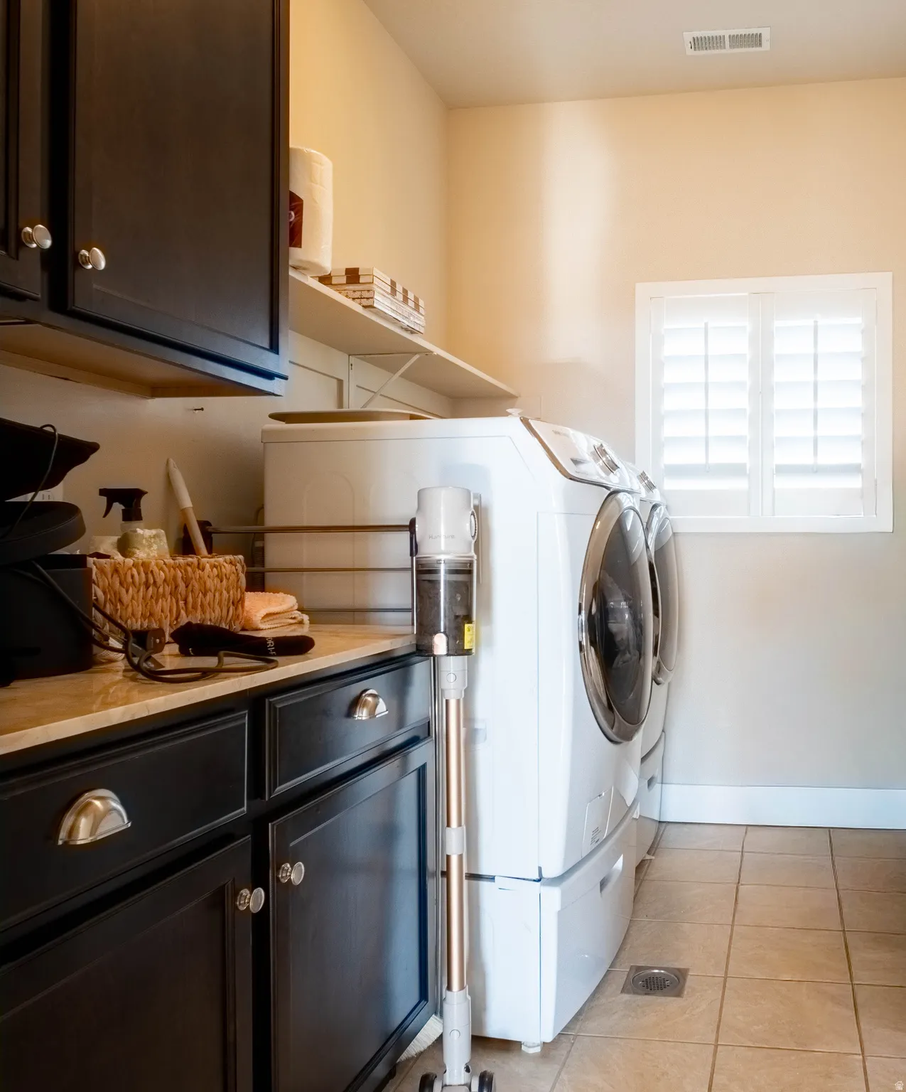 Laundry room featuring cabinet space, light tile patterned flooring, and washing machine and dryer