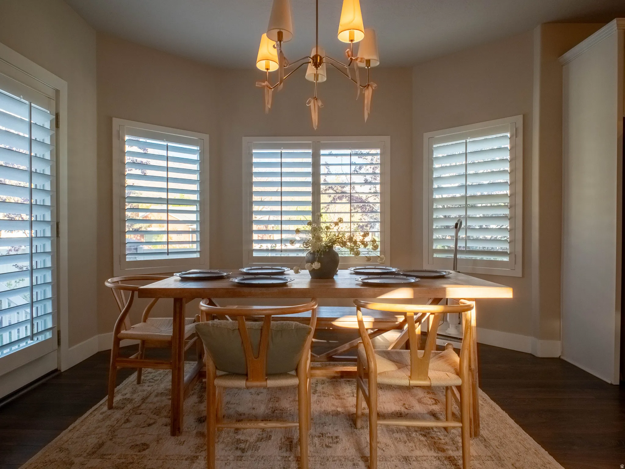 Dining room with dark wood-type flooring, hanging lights, and plenty of natural light