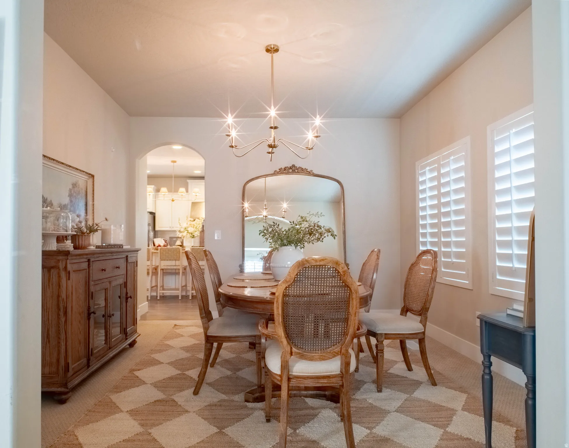 Dining room with suspended lighting, arched walkways, and light carpet