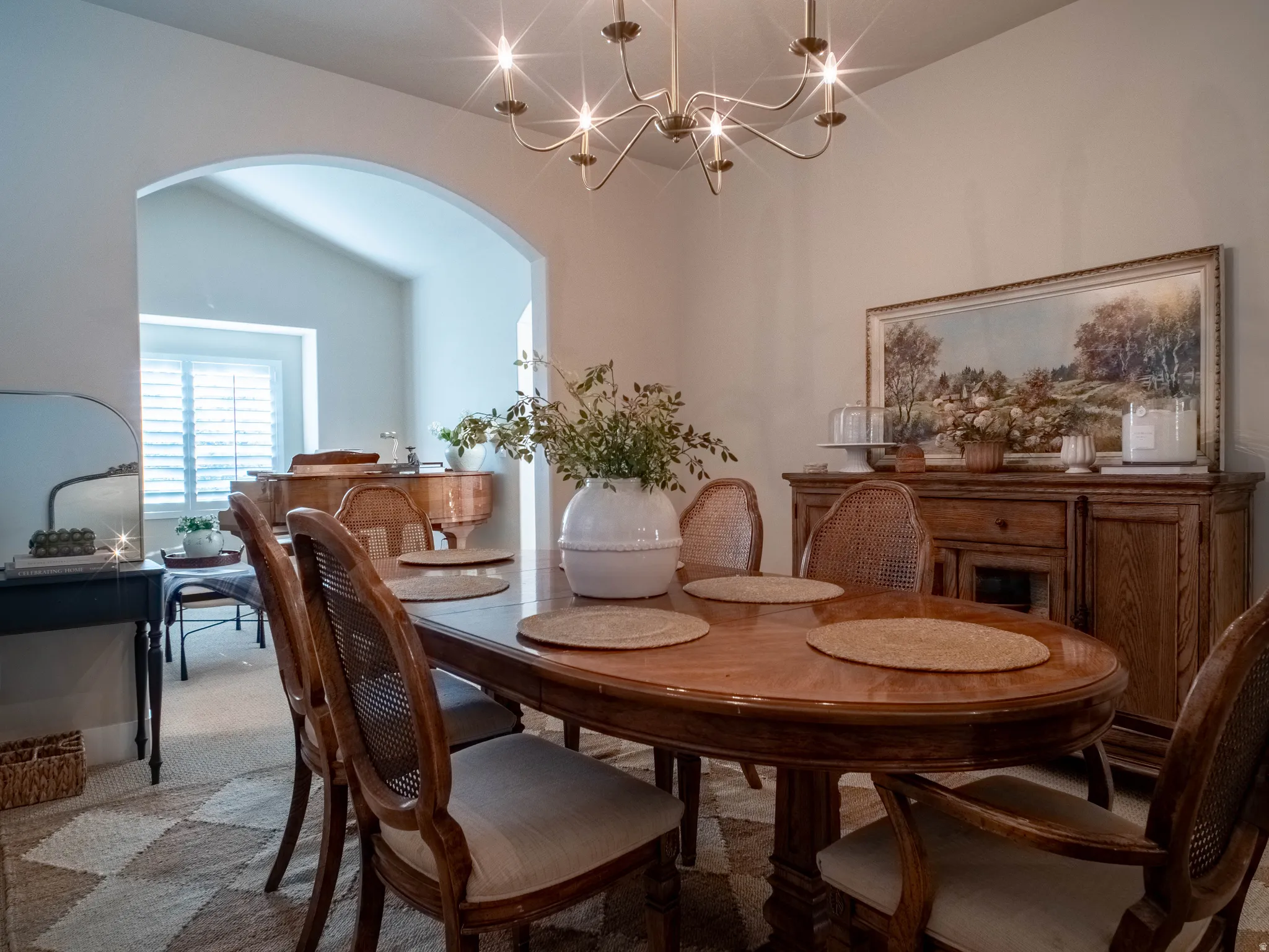 Carpeted dining area with arched walkways, a chandelier, and lofted ceiling