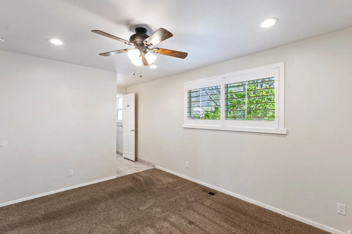 Empty room with light carpet, a ceiling fan, and recessed lighting