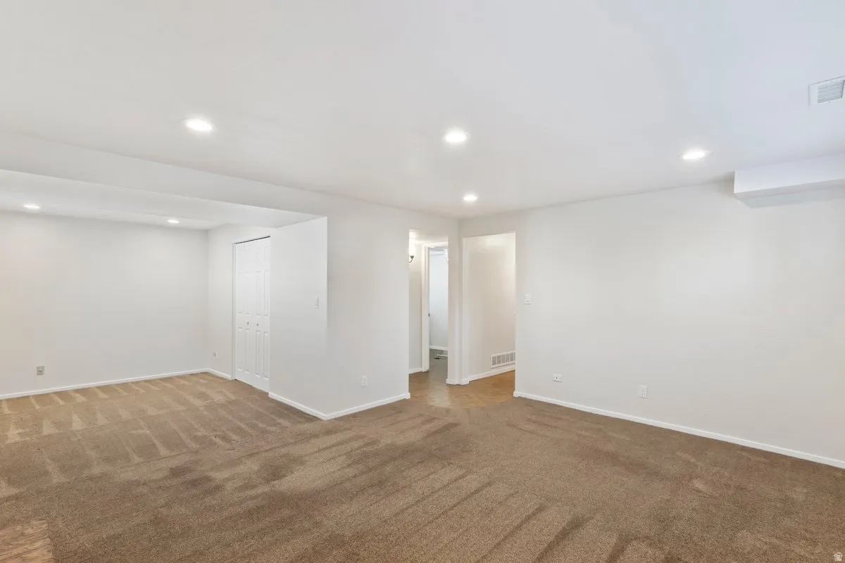 Empty room with dark colored carpet and recessed lighting