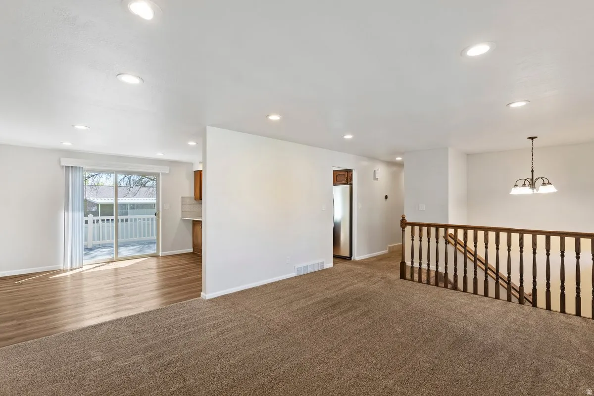 Unfurnished room with dark colored carpet and suspended lighting