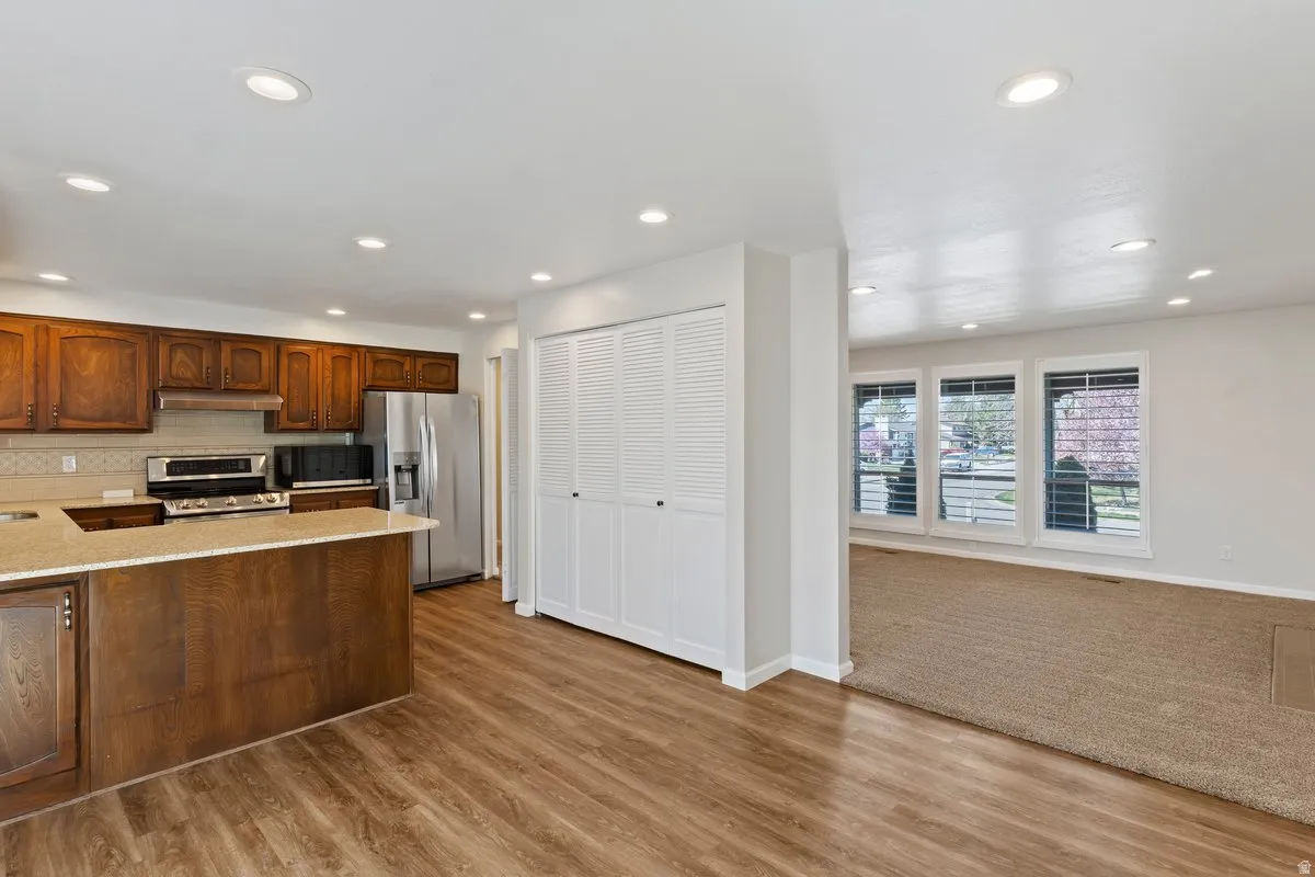 Kitchen featuring stainless steel appliances, recessed lighting, light stone countertops, tasteful backsplash, and a peninsula