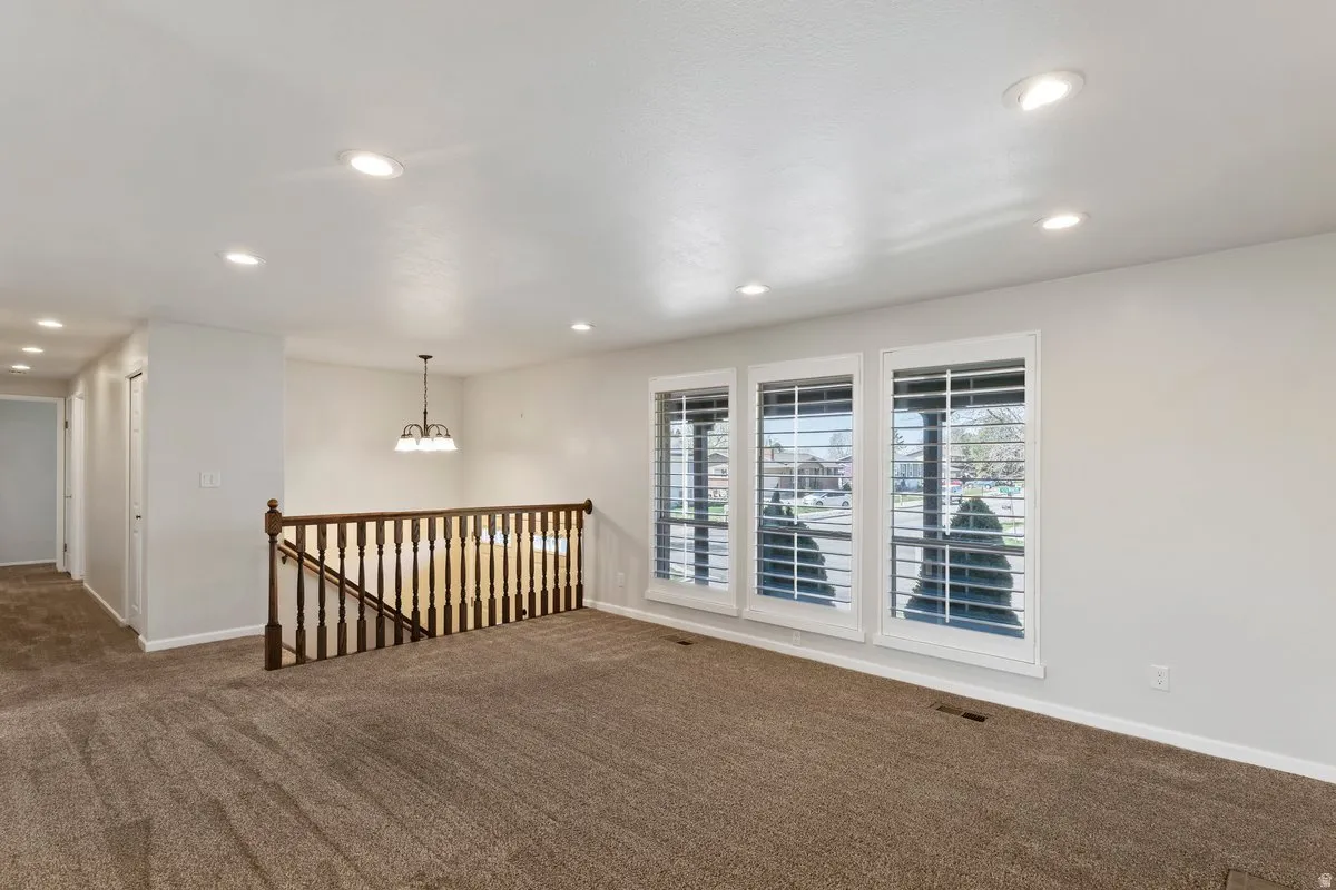 Empty room featuring dark carpet and a chandelier