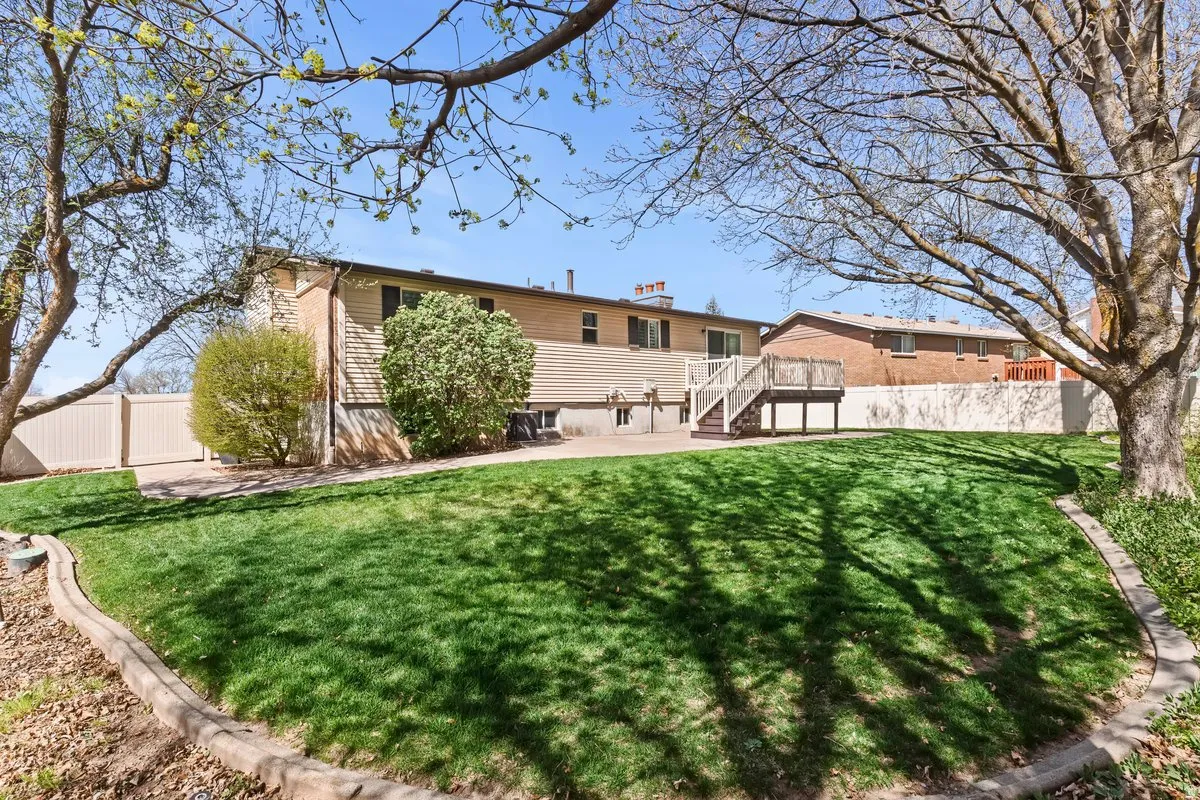 Rear view of house with a fenced backyard, a wooden deck, and a patio