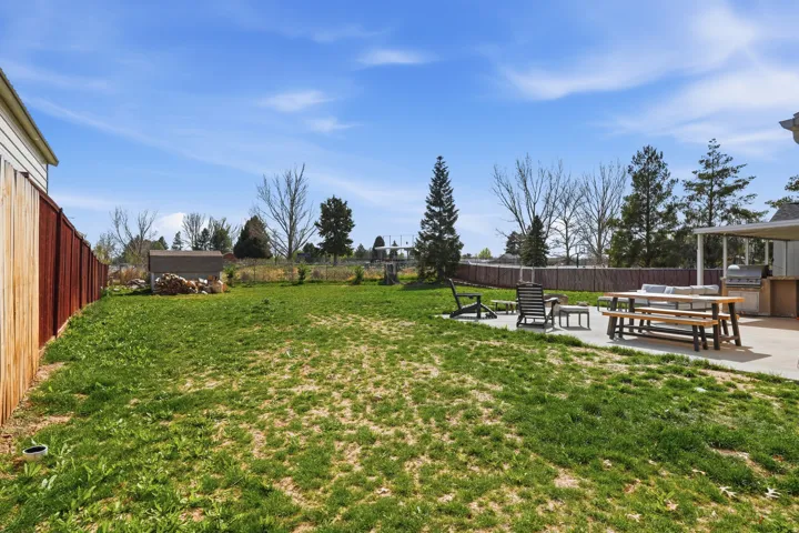 Fenced backyard with a patio area, an outdoor kitchen, and an outdoor fire pit