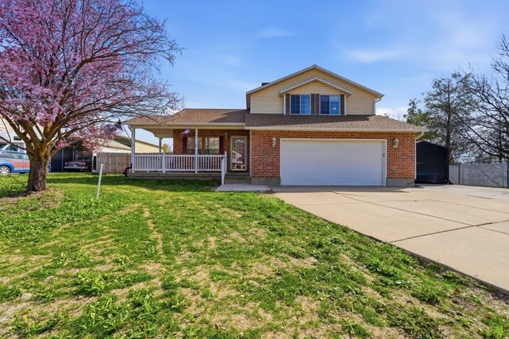 View of front of house with covered porch, driveway, a garage, brick siding, and a shingled roof