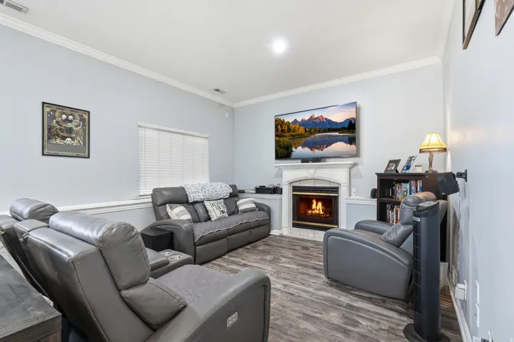 Living room featuring crown molding, a tiled fireplace, and wood finished floors