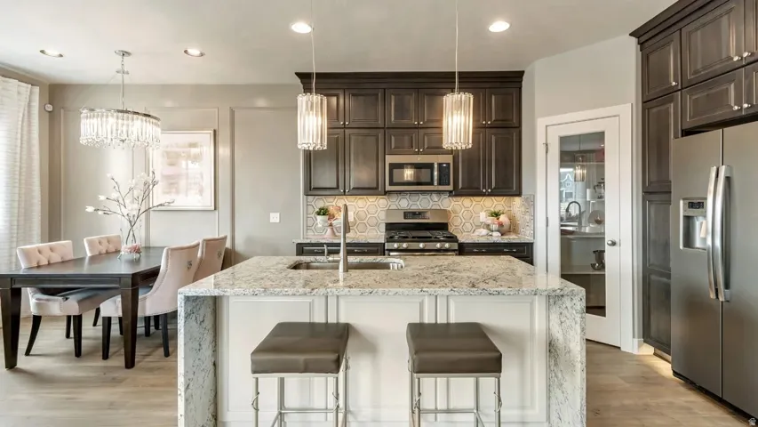 Kitchen featuring light stone countertops, stainless steel appliances, decorative backsplash, light wood-style floors, and dark wood finish cabinets