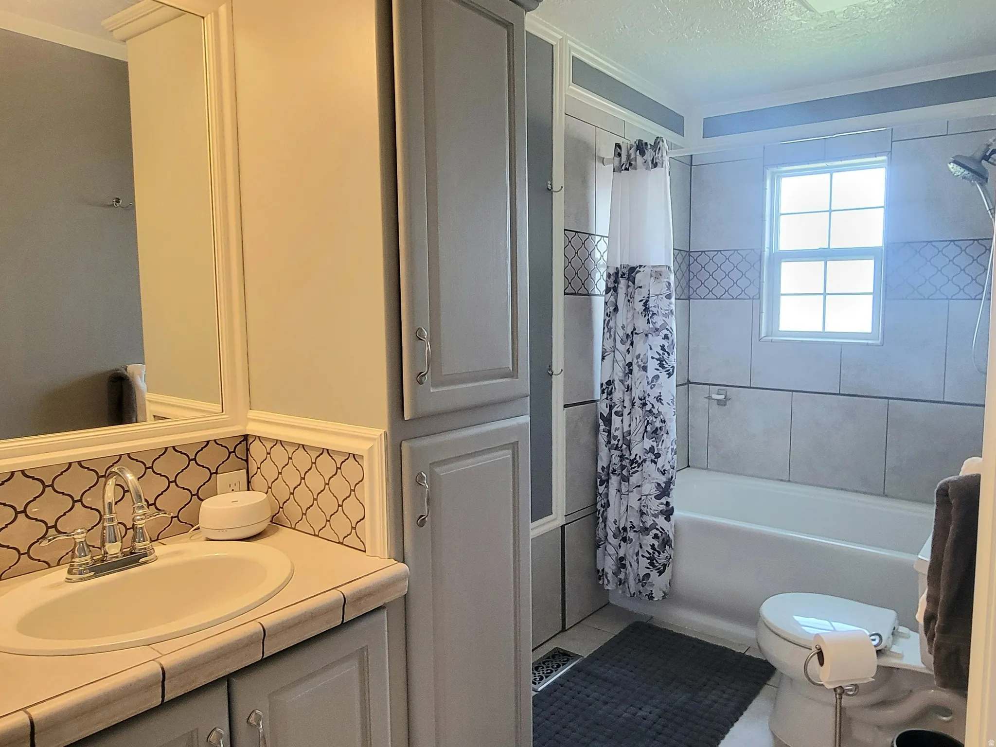 Bathroom with vanity, shower / bath combo, decorative backsplash, and crown molding