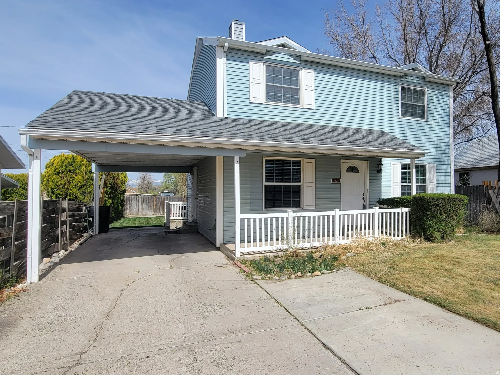 Traditional-style home featuring a porch, driveway, a shingled roof, a chimney, and a carport