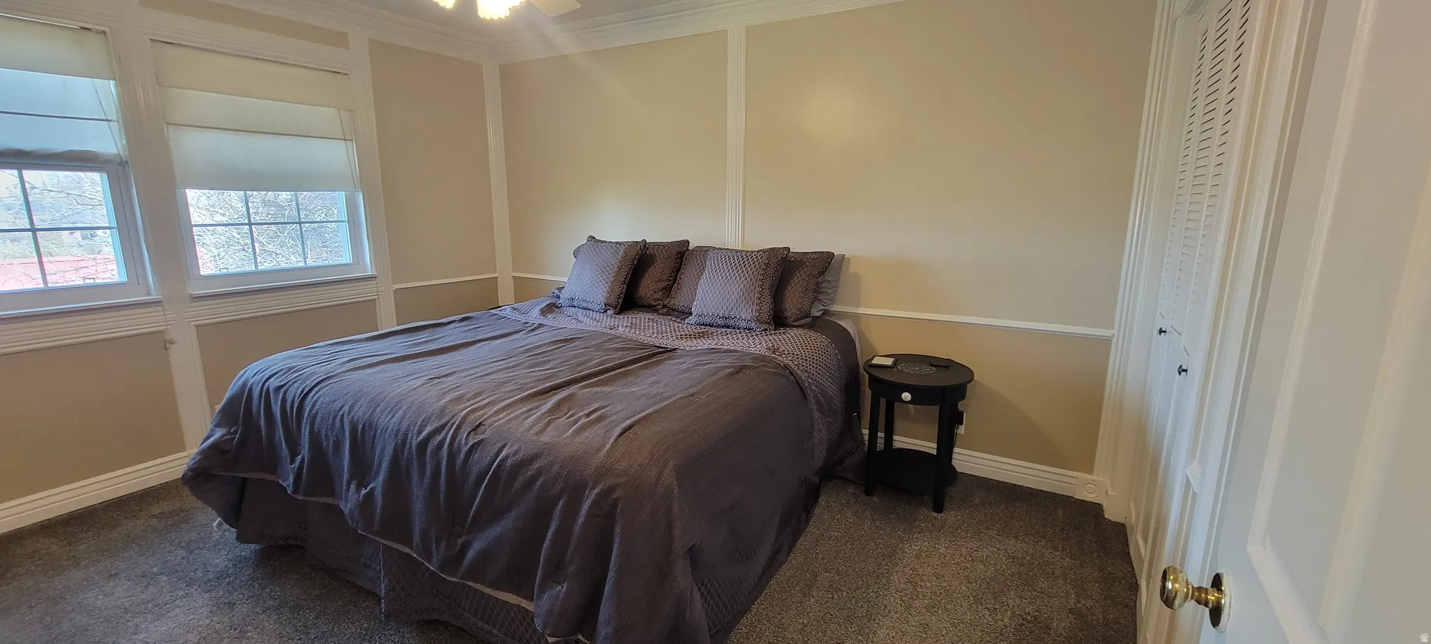 Bedroom featuring dark carpet, ornamental molding, and ceiling fan