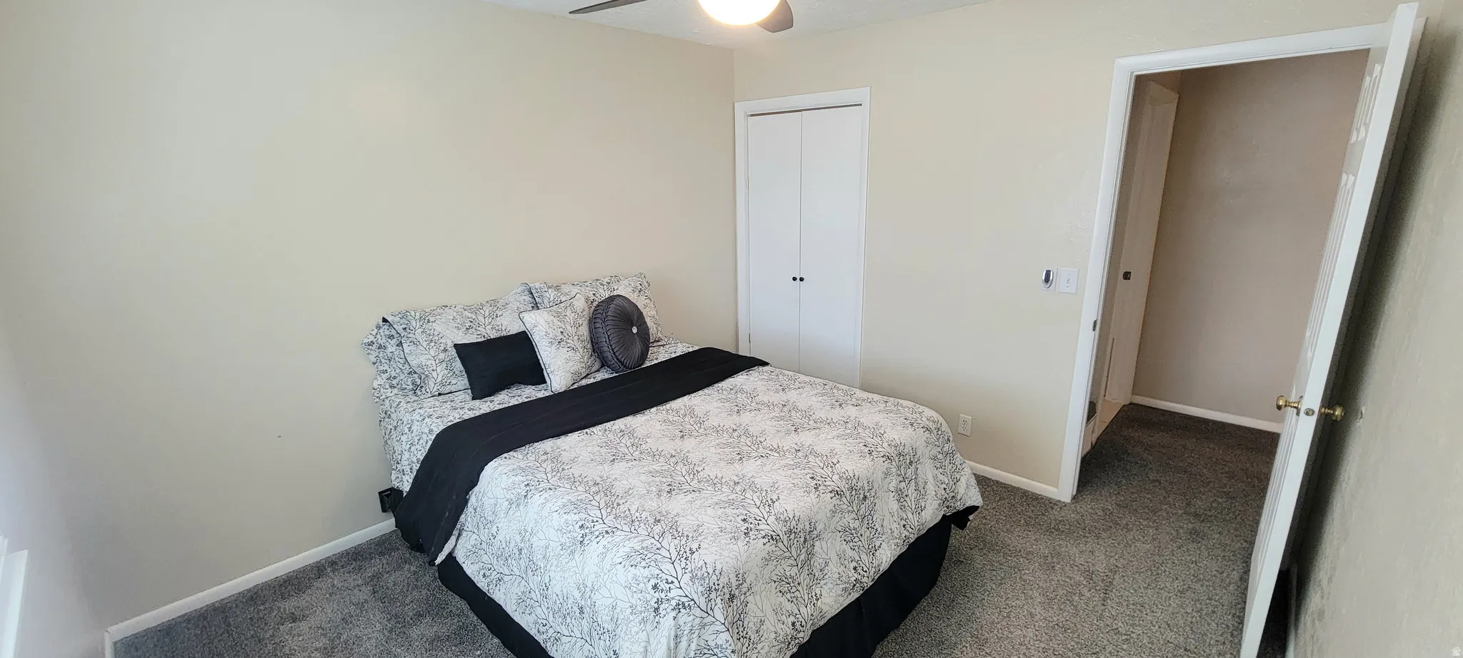 Bedroom with dark colored carpet, ceiling fan, and a closet