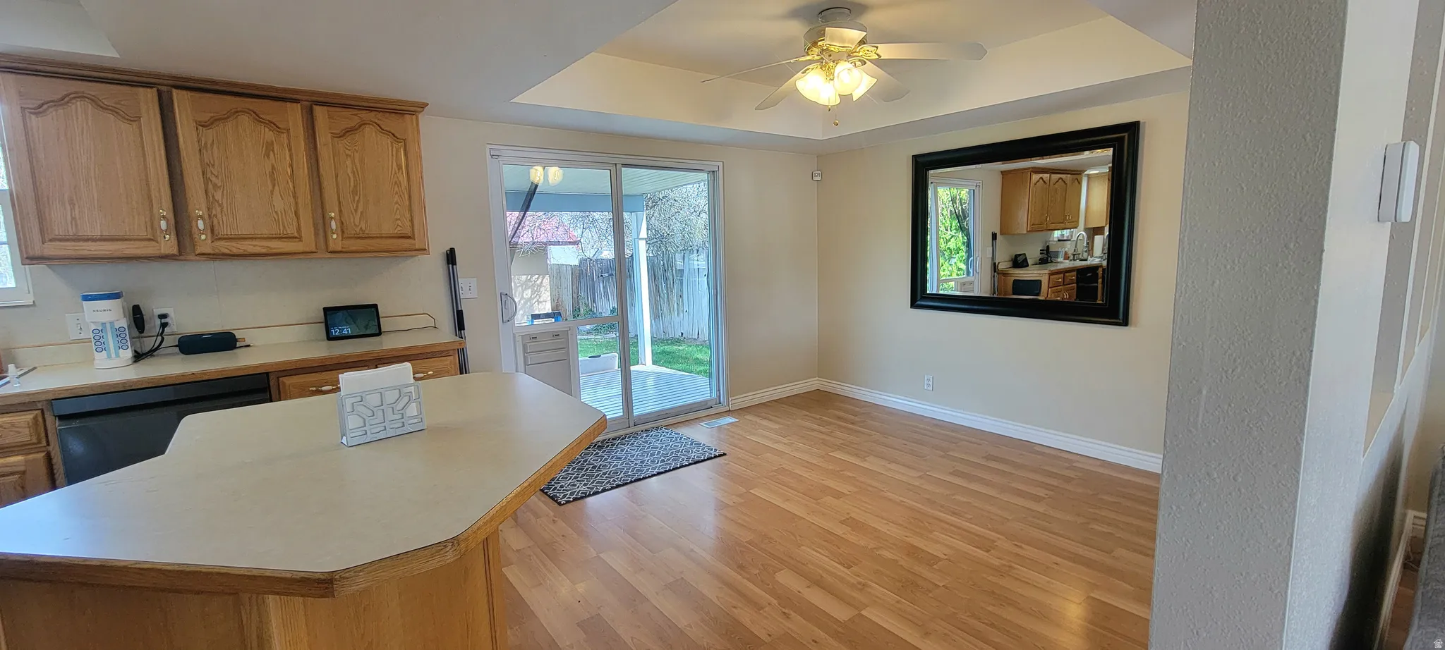 Kitchen featuring light countertops, dishwasher, light wood-style floors, a ceiling fan, and a center island