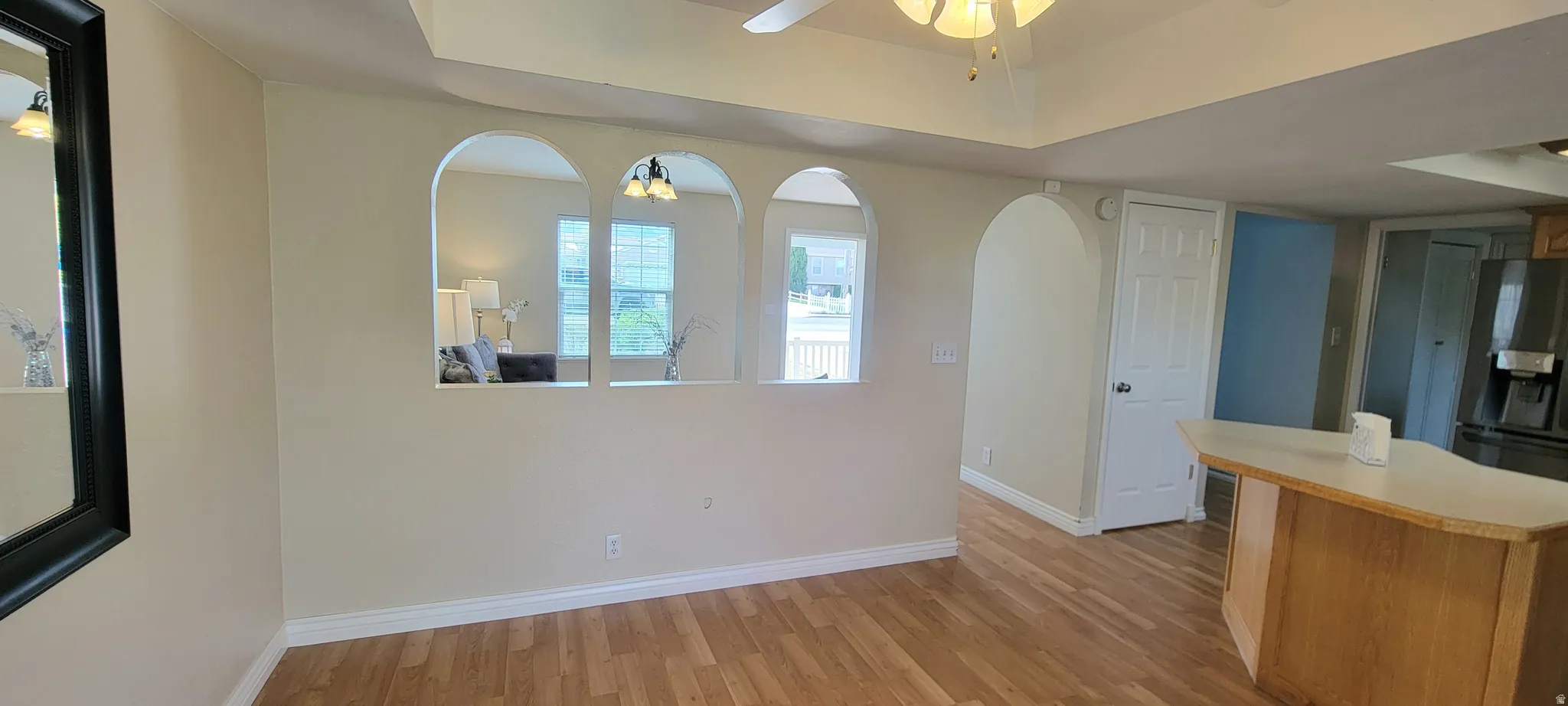 Kitchen featuring light countertops, a ceiling fan, light wood-style floors, arched walkways, and a center island