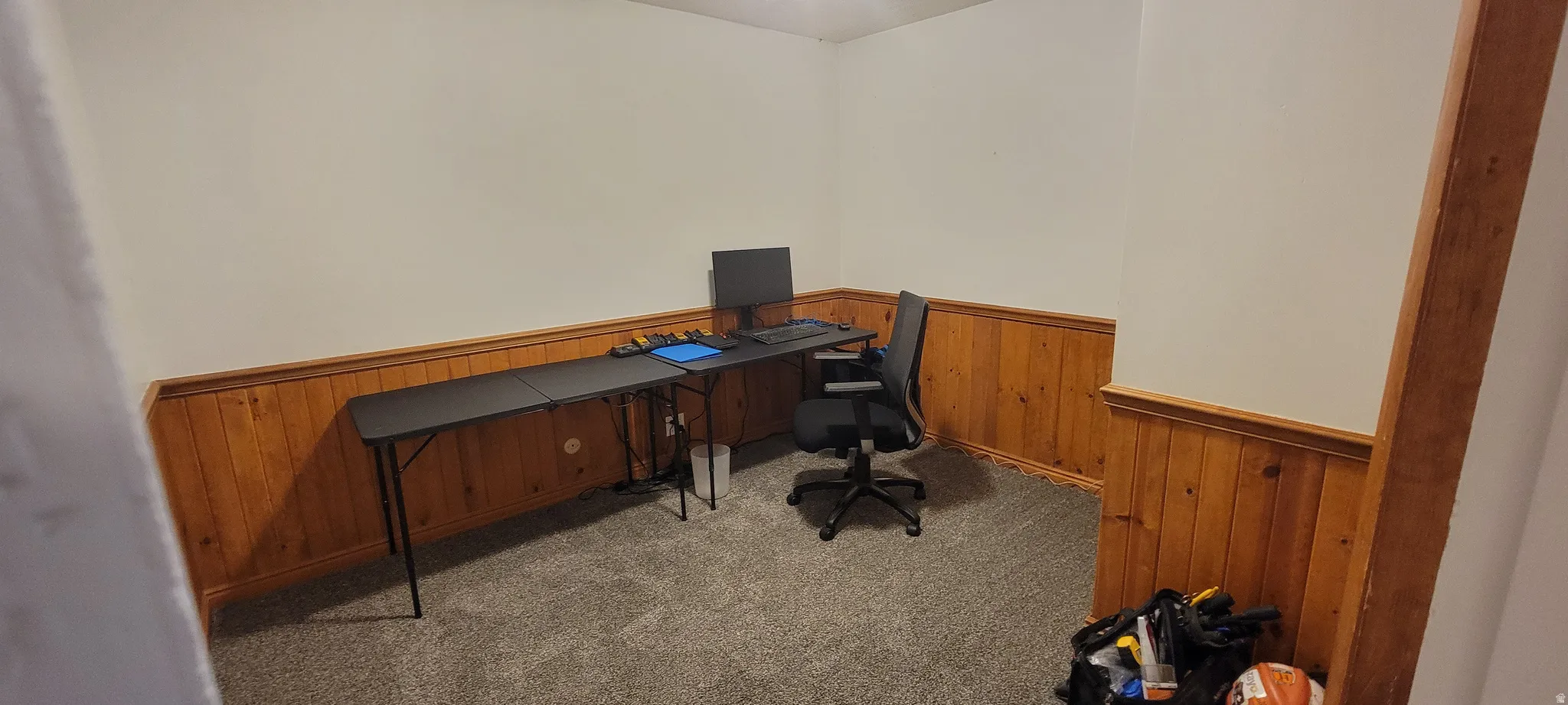 Carpeted office with wood walls and a wainscoted wall