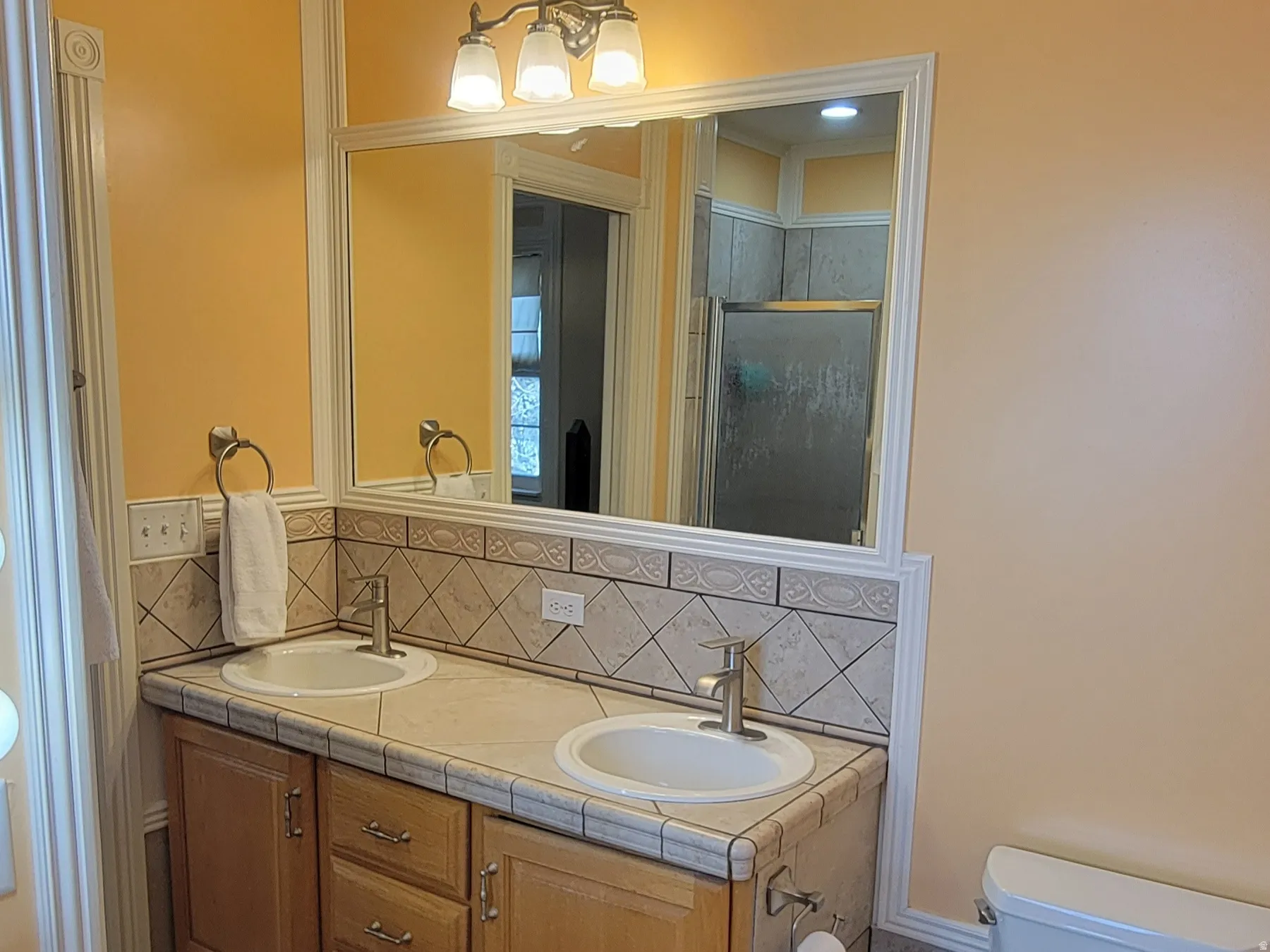 Bathroom with double vanity, ornamental molding, tasteful backsplash, a stall shower, and light tile patterned flooring