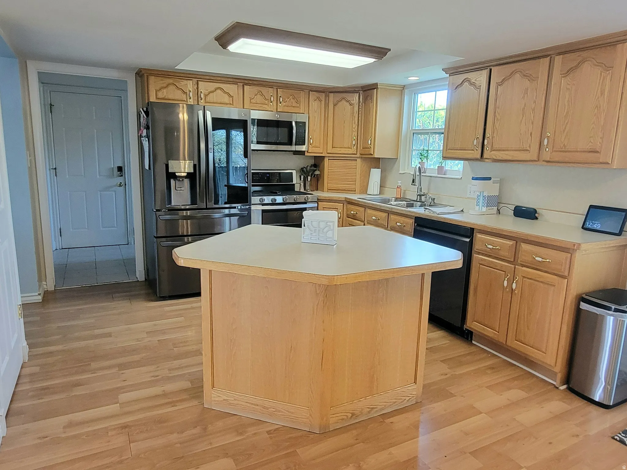 Kitchen with a center island, stainless steel appliances, light countertops, and light wood-style floors