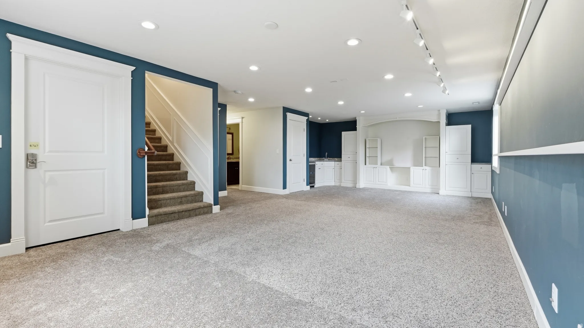 Expansive room with recessed lighting, track lighting, built-in cabinetry, a built-in wet bar, and carpeted flooring