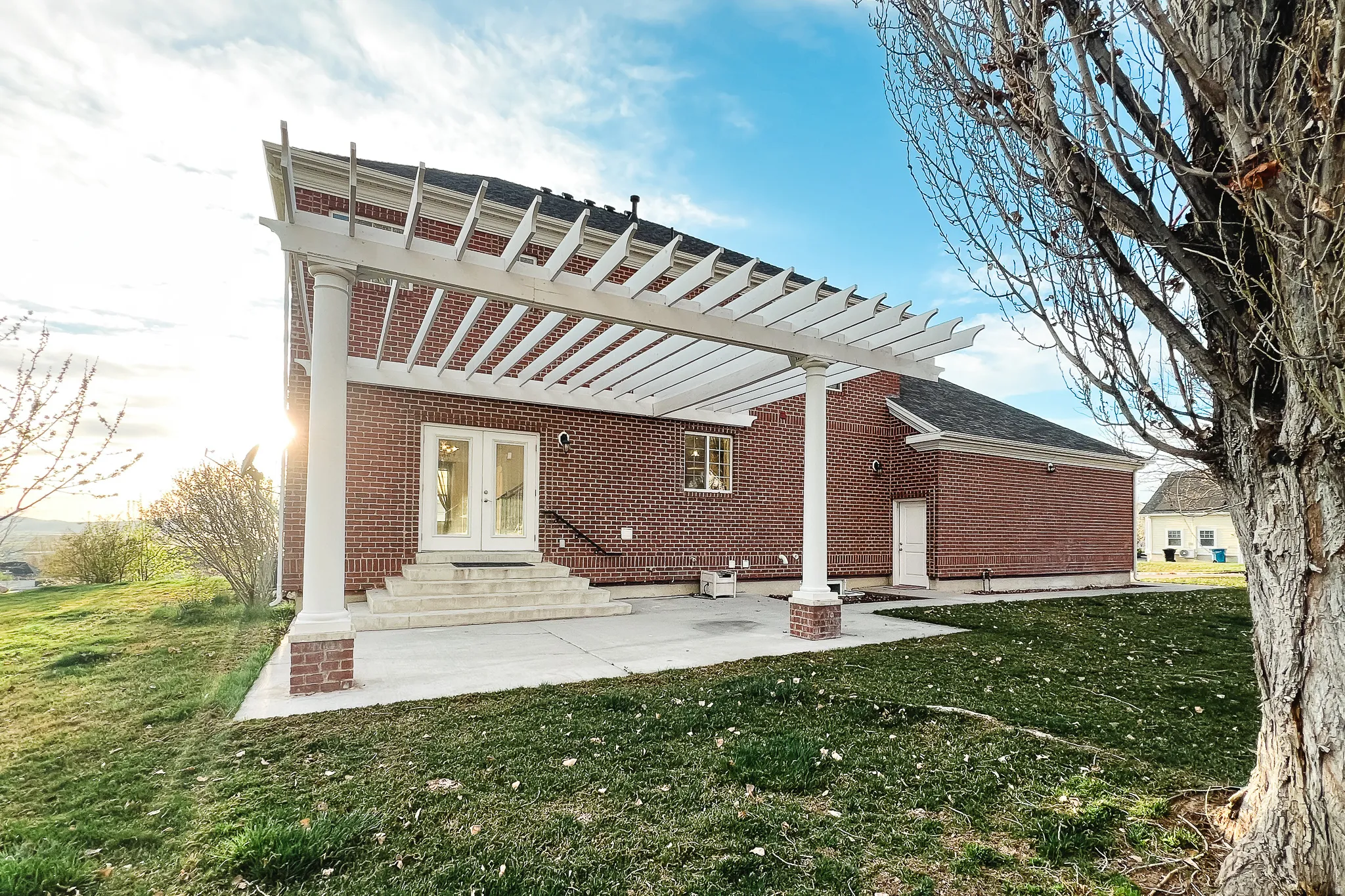 Back of property featuring a yard, a patio area, brick siding, and entry steps