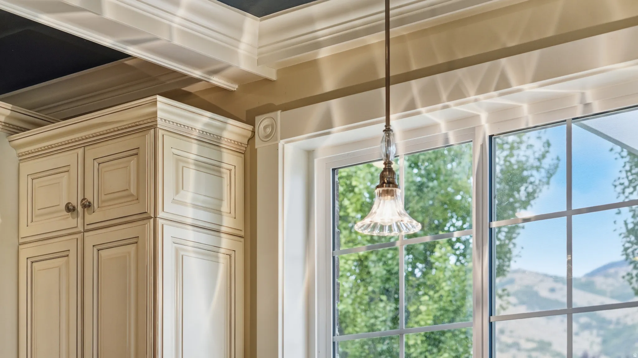 Custom cabinetry with decorative molding and hardware, grid-pattern windows, and a clear glass pendant light fixture