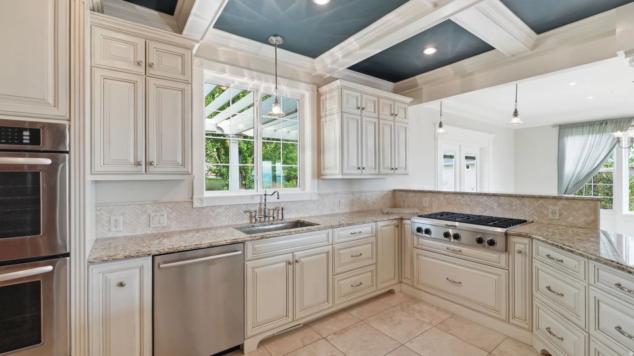 Gourmet kitchen with white cabinetry, stainless steel appliances, granite countertops, and a coffered ceiling