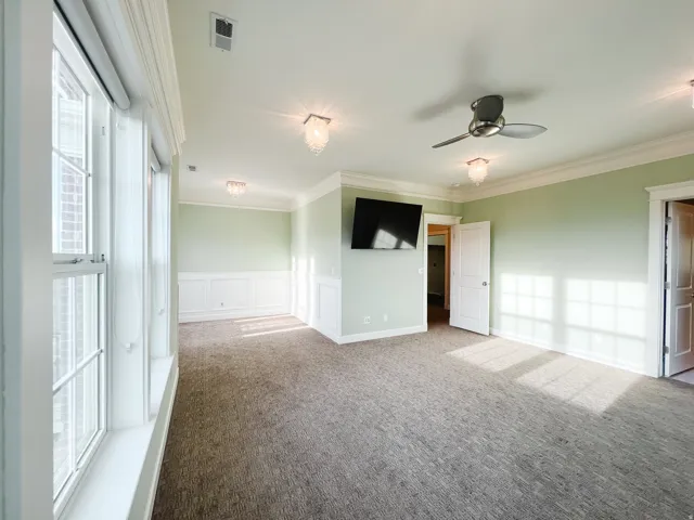 Unfurnished room with plenty of natural light, carpet floors, a wainscoted wall, crown molding, and a decorative wall