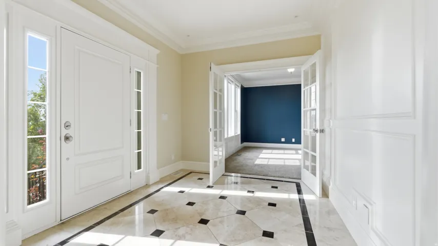 Entryway featuring a decorative inlaid tile floor, a paneled front door with sidelights, and French doors leading to an additional room
