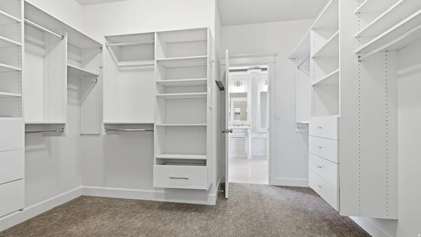 Walk-in closet with ample white built-in shelving, multiple hanging rods, and integrated drawer storage